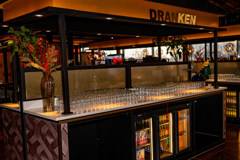 Barhoek in Wereldrestaurant Breepark met de tekst 'Dranken' verlicht boven de bar.